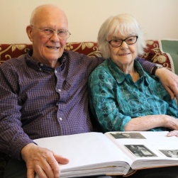 Barry and Enid Reeves, 91, dementia research participants at home on their sofa holding a photo album.