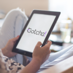 Close up of hands holding a computer tablet screen showing the 'Gotcha!' study logo